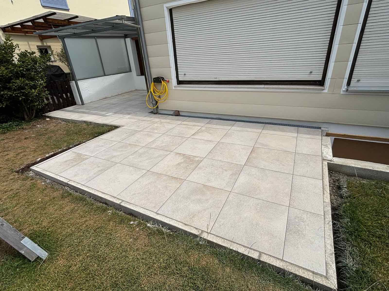 Neue Terrasse aus hellen Großformatplatten an einem Wohnhaus