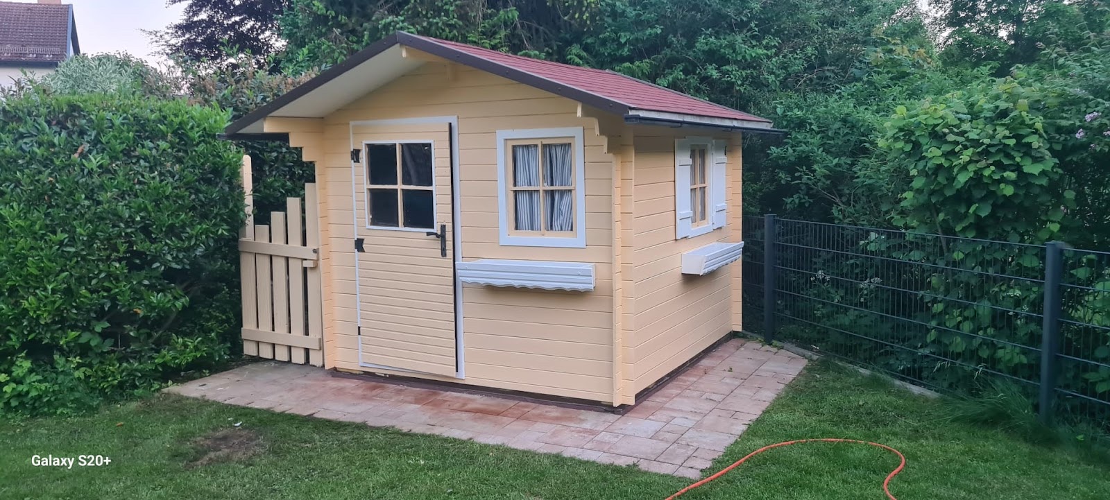 Gelbes Gartenhaus aus Holz auf einem Plattenfundament im Garten